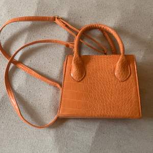 Handväska i orange med losstagbar axelrem