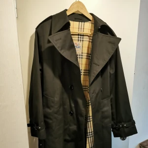 Trenchcoat kappa svart - Svart trenchcoat kappa, vattenavvisande och vindtät. Kappan kan passa storlek M-XL pga oversize.  Snabb hämtning prioriteras.