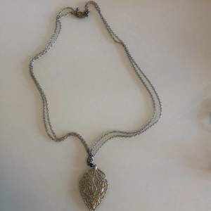 Ett halsband med två kedjor o ett stort blad som smycke, silver. 