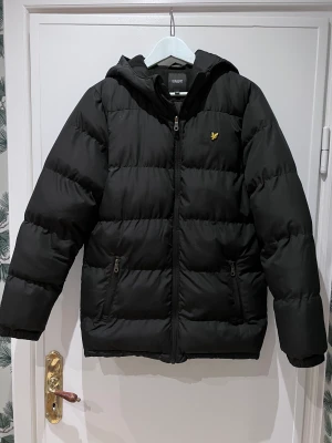 Lyle & scott Puffa jacka  - Lyle & Scott jacka med luva. Färg svart Storlek 14-15 år