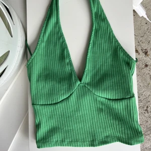 Grön halterneck topp - Nyskick! Stretchiga material så jag skulle säga att den passar XS och M också. 