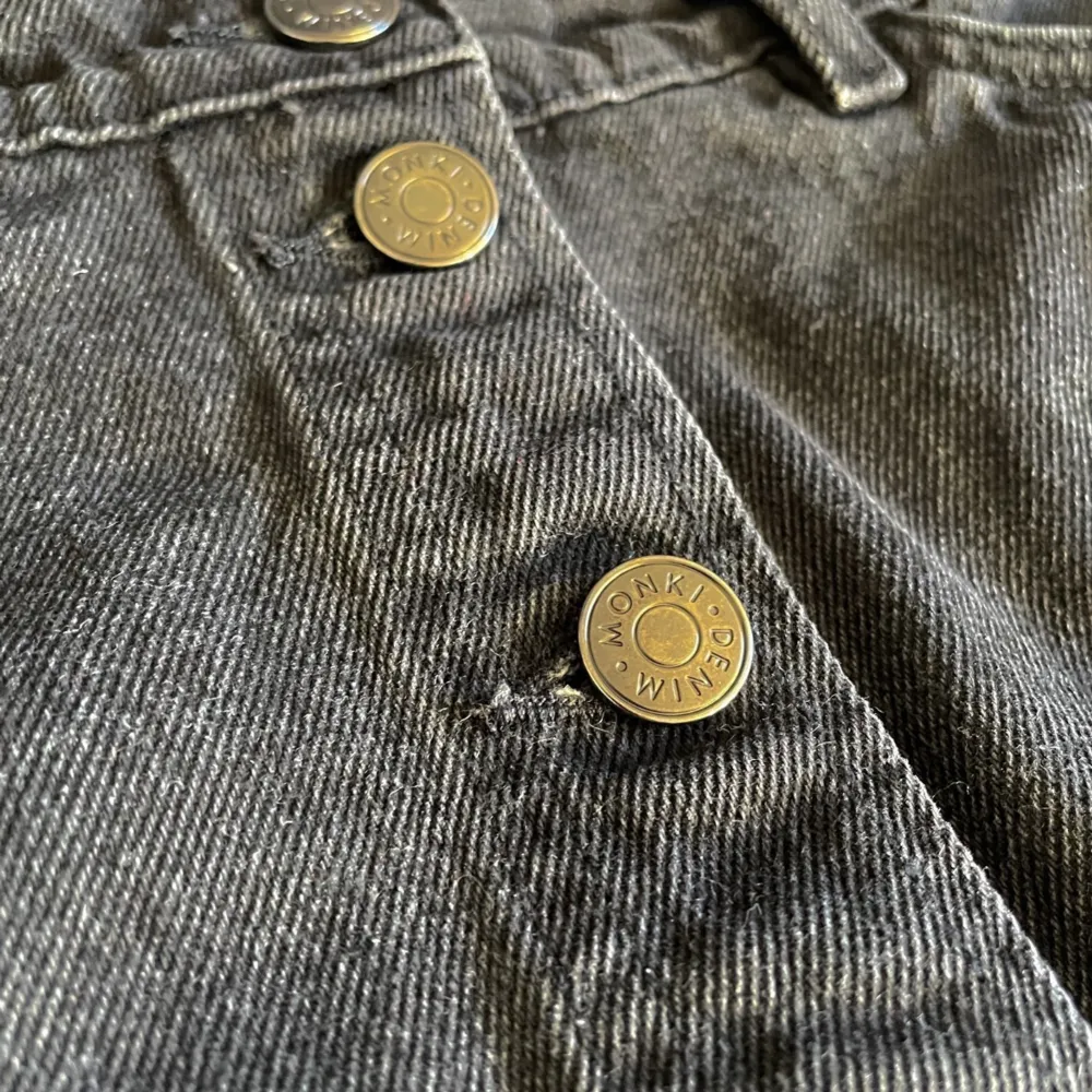 Fantastiskt fin A-linjekjol från Monki i äkta stentvättad jeans/denim.   Nypris 600 kr.  Kjolen är helt svart i verkligheten, inte alls lika ljus och ”flammig” som på bild 2 och 3 men där syns mönstret bättre.  Stängs med knappar längs hela framsidan.. Kjolar.