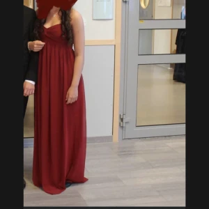 Balklänning - Supersöt balklänning utan axelband. Använd 1 gång. Tyvärr har det blivit ett litet hål bak till på klänningen, går säkert att laga för den händige (se bild 2). 