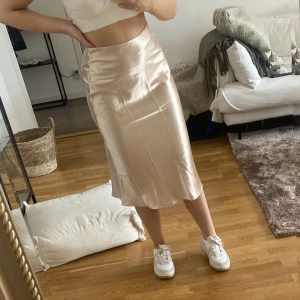 Kjol - Rosa/beige satinkjol. Sitter jättefint med dragkedja på sidan. Aldrig använd.