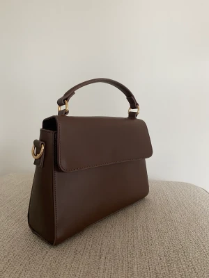 Handväska - Säljer denna handväska i en nyans av brun. Ett större fack och två mindre. Frakt tillkommer💕