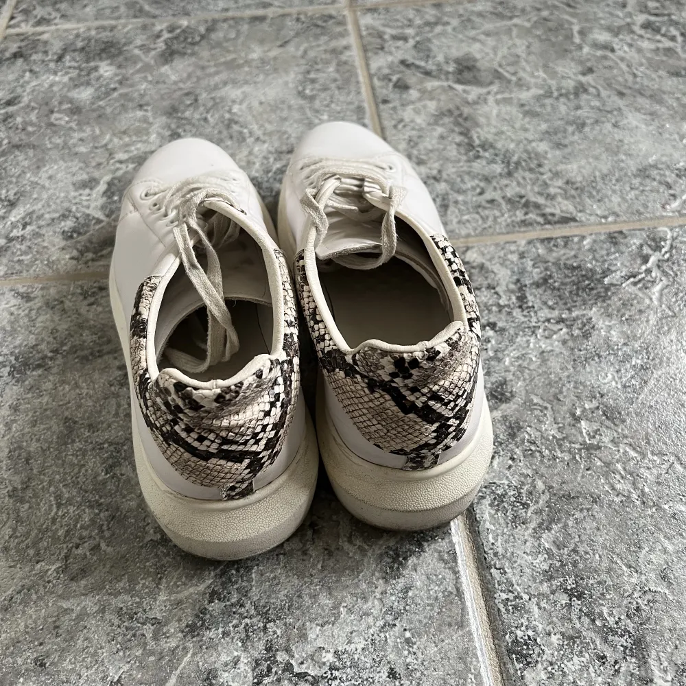 Vita sneakers med orm skinns detalj baktill, använda men fortfarande i fint skick🐍🤍🤍 köpta på nelly för längesen. Skor.