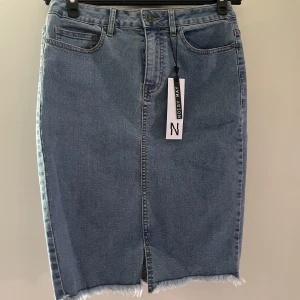 Supersnygg jeanskjol tight passform NY  - Ursnygg ljus jeanskjol, perfekt nu till sommarn. Endast testad, med lappen kvar! Sitter tight kring kroppen & utmärker dess former. Fransig kant nedtill & en slitz på framsidan 