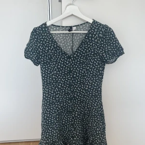 Klänning  - En så söt grön-blommig klänning från H&M.   Storlek 36 men passar snarare 34   Säljes pga: blivit för liten 