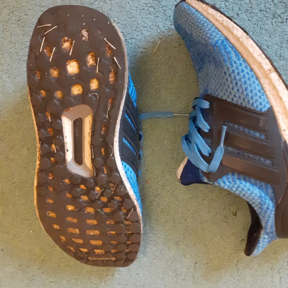Ett par blåa adidas ultraboost skor som nästan aldrig är använda men undersulan gar gått av och vi har fixat den . Skor.