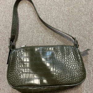 Axelväska - Snygg axelväska i en snygg olivgrön färg. Ormskinnsmönster. Från ginatricot. Säljs ej mer! 200kr + frakt