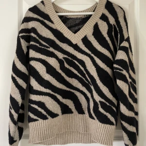 Zebramönstrad tröja - Stickad tröja i zebramönster med v-ringning. Köpt på na-kd.