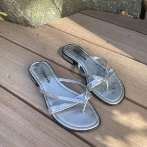 Tamaris sandaler  - Ett par silvriga sandaler från tamaris med glitter detaljer. Aldrig använda utomhus men är lite svarta vid hälen på insidan på ena skon (se bild). Annars fint skick!