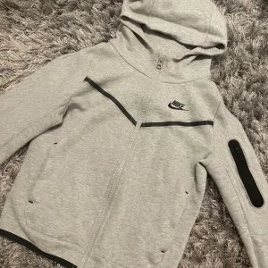 Nike Tech - Jag säljer denna gråa Nike tech i barnstorlek M, då den inte kommer till användning. Säljer för 500kr (priset kan diskuteras). 
