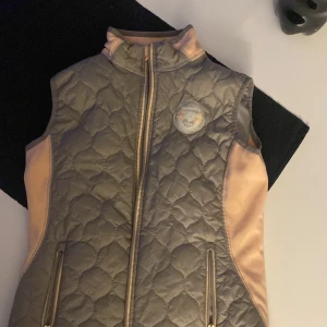 Täckväst /väst/ att ha i stallet - Denna väst är testad 1 gång. En täckväst som är bra att ha när man är o rider(ingen skyddsväst) men så barnen inte blir kall på kvällen. Vår/höst o kalla kvällar är denna perfekt att ha. Den är tvättad efter den användes.Stl 160