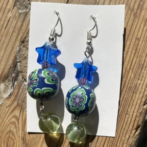 Blågröna örhängen - Supercoola blågröna örhängen med blommor och stjärnor🌺⭐️💙 Helt nya och oanvända eftersom de nyligen är egengjorda av mig!💎ca 6 cm långa💞💞