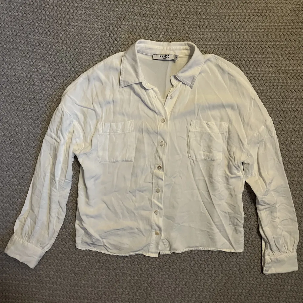 En vit skjorta från na-kd. Tyvärr krympte skjortan i första tvätten vilket gjort att den är för liten för mig. Skulle säga att den är som en storlek 32 snarare än 34, övrigt i fint skick!. Skjortor.