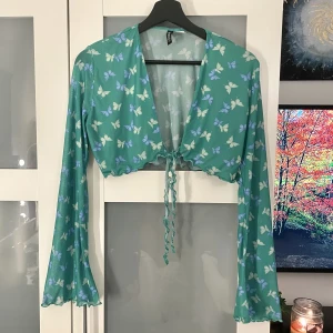 Grön topp med knytning - Så fin topp med knytning fram och vollangarmar! I meshmaterial men inte genomskinlig på kroppen, ärmarna är lite genomskinliga!