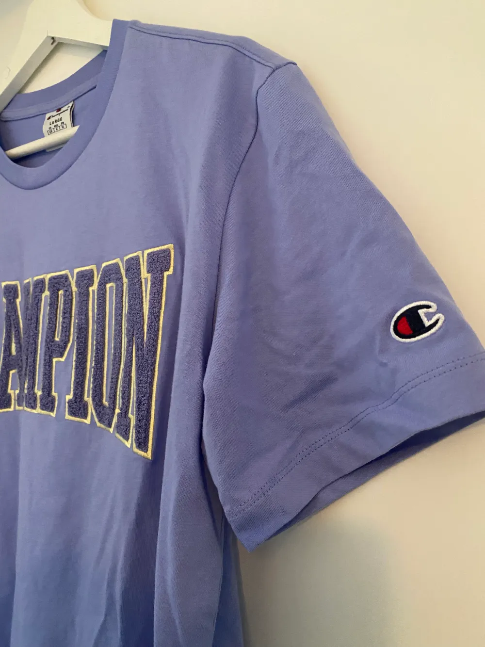 T-shirt från champion i en pastellila färg med broderad text med fyllning. Enbart använd 2/3 tillfällen!. T-shirts.