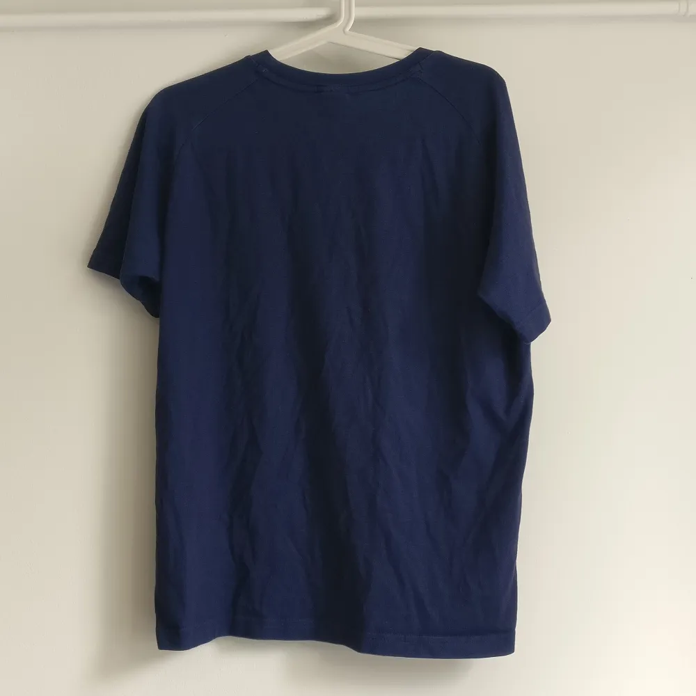 Blå lite melerad t-shirt i bomull, med tryck över bröstet. Bra träningströja eller vardagströja. Köparen står för frakt. T-shirts.