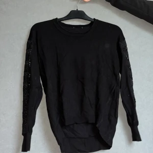 Svart långärmad tröja med spets ärmar - Svart lång ärmad tröja med skönt material. Mönster på armarna 
