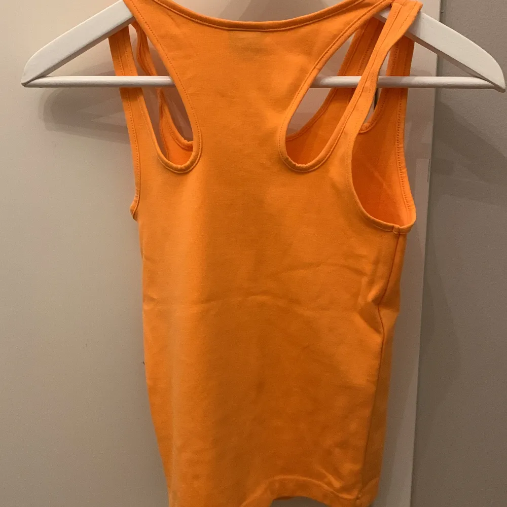Ett orange linne som sitter lite tajt Aldrig använd. Toppar.