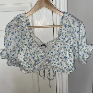 Blommig topp - Fin topp från gina vit med blåa blommor, bra skick, stl M