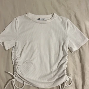 Ribbad vit topp med knytdetalj - Ribbad vit topp från zara med knytdetalj,använt fåtal gånger,stl M men skulle säga att den även passar s/xs 