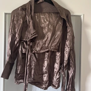 Brun/guld/bronsigt set från Gina - Ett snyggt set från Gina Tricot som aldrig använts och är ett onödigt köp! Storlek 40 sitter jättefint men för stort på mig. En topp som går att knyta med en medellång kjol med slits bakom! 