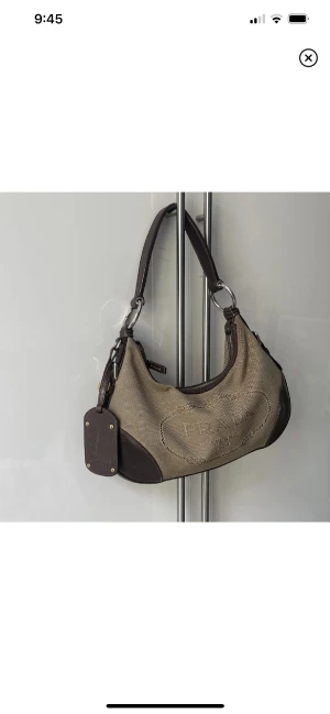 Vintage Prada väska i Linne - Prada väska i brunt linne med läderdetaljer! Denhar en liten fläck på framsidan (se bild) i övrigt väldigt gott skick. 🫶🏼 Dustbag tillkommer!  Priset är ej diskuterbart  