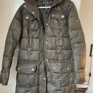 Kappa Barbour - Sparsamt använd vinterjacka från Barbour. Brun med gulddetaljer. Skärp och fuskpäls till luvan saknas men går att sätta på en annan päls. Köparen betalar frakt.