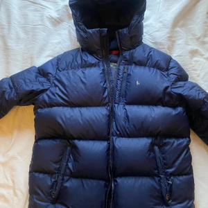 Snygg Ralph Lauren jacka - Köpte jackan här på Plick men  säljer den vidare igen pga fel storlek. Den är i använt skick men har inga defekter förutom loggan som är lite avskavt! Den är i dun så  är väldigt varm och passar bra nu till vintern. Passar herr&dam skriv för mer info😇 