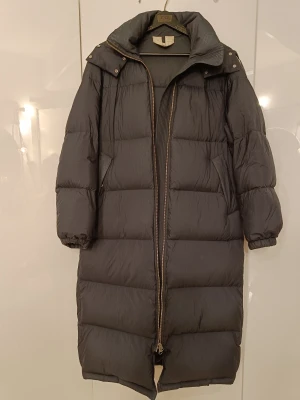 Arket dunjacka stlk S  - Arket. Lång dunjacka. Stlk S. Passar även större. Använd ganska sparsamt. Spår av användning i form av färgskiftningar jag försöker visa med förstärkt ljus-främst vid krage, fickor och ärmslut. Se bilder. 