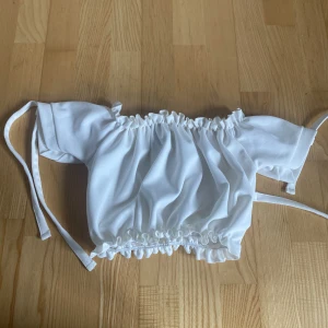 Vit off-shoulder topp - Vit off-shoulder topp med rosetter på ärmen. Från New Look, köpt på Zalando. Använd fåtal gånger.