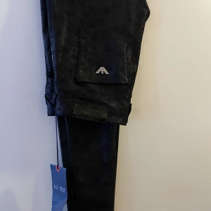 Armani jeans byxor - Glittriga, mockaliknande material. Strl. 27, motsvarar xs. Smal passform. Aldrig använda. Nypris 2000:-