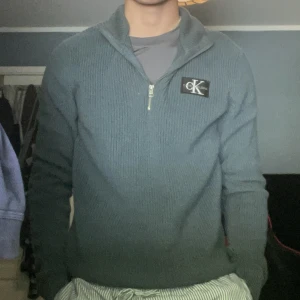 Mörkgrön Calvin klein half zip - Koftan är väldigt skön att ha på dig, oberoende på hur mycket man drar upp dragkedjan, jag har haft på mig den runt 2 gånger, den är i en mörkgrön/turkos färg. Den är i storlek 16, men den passar bra på mig som är 14 och 176 lång.