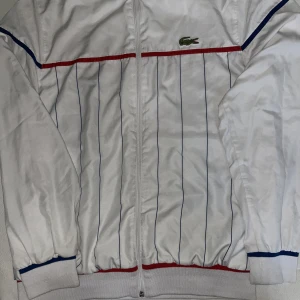 Lacoste kofta - Ganska så fin kofta inför den varma sommaren nu. Ett ganska så bra skick. Size 4  Lotten på koftans bröst e 86-89cm och midjan är 62-64cm