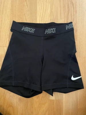 Nike shorts - Svarta Nike shorts med vita detaljer. Använda ett fåtal gånger men kommer inte till användning längre.