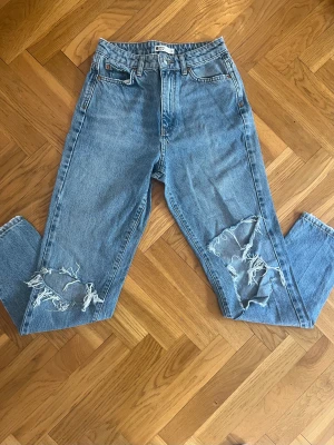 Gina Tricot Jeans - Fina jeans från Gina Tricot i använt skick. Hålen på benen har gått upp och vidgats, annars är det inga slitningar.