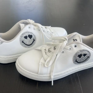 Smiley sneakers  - Vita smiley sneakers från Zalando. Storlek 38! Använda 1 gång. Köpt för 500kr säljer för 300. Helt vita utan några skador, glittret är fint och helt!