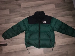 The North Face Nuptse 700  - Jackan är extremt bra skick. Den sitter jätte bra på mig, värmer väldigt bra och är väldigt nöjd med den. Säljer den alltså för att jag tröttna på färgen men det är en väldigt fin emerald grön. Generellt perfekt jacka till vintern! Kom med eget bud!