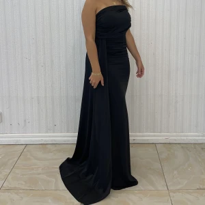 Klänning  - Svart klänning med släp på sidan