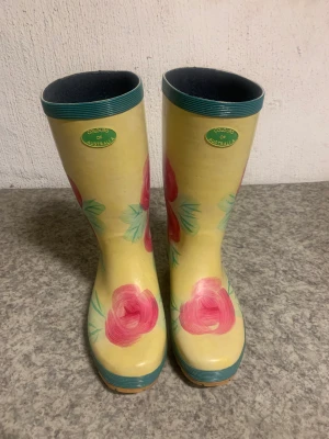 Gummistövlar med blommor på - Gula gummistövlar med rosa blommor på säljes för 200kr. Jag kan träffas i Stockholm city eller så trycker du på köp knappen så skickar jag dem till dig. 