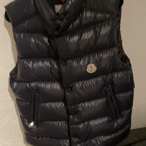 Moncler Tibb Gilet - Säljer nu min MonclerTibb Gilet i Navy blue. Västen är i väldigt gott skick 9/10, har själv använt den en gång, nypris på denna är 7 325kr. Den har storlek 1 vilket motsvarar S men bär själv M och passa mig väldigt bra. Bara att höra av er vid fundering
