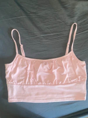 Rosa topp - Snygg rosa croptop från H&M som inte kommer till användning längre. Den är i fint skick och endast använd fåtal gånger Har justerbara axelband och är inte genomskinlig Kontakta gärna för fler frågor eller bilder!🌸