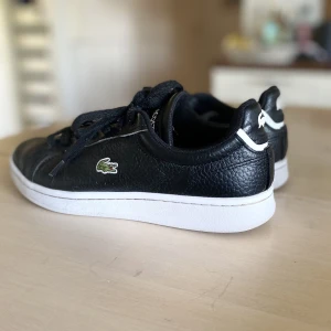 Lacoste skor  - Svarta Lacoste skor i storlek 38. I bra skick. Orginalpris 1000