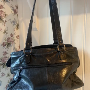 Svart rymlig handväska - Väldigt rymlig och bra väska med maassa fack! Kan ta fler bilder om det behövs! Inte bästa skick men jag tycker den är väldigt fin ändå och ser lite vintage ut!