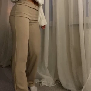 Beige/bruna byxor - Beige/bruna byxor från Nelly i storlek xs. Använt fåtal gånger. Midje mått rakt över 34 cm, innerbenslängd  84