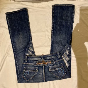 Bigrexy jeans  - Snygga unika jeans som säljes billigt. De är i bra skick, dock är det slitage på dragkedjan, men detta påverkar inte utseendet på jeansen och det går fortfarande att stänga dragkedjan. Tyget är elastiskt. Midja: 35cm Grenmått: 19cm. Innerbenslängd: 79cm. 