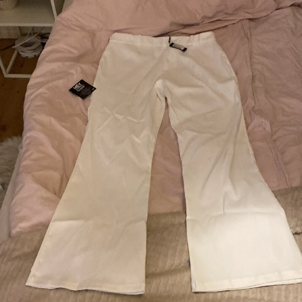 Helt oanvända vita kostymbyxor som är low waist och har ett litet utsväng nere vid benen . Jeans & Byxor.