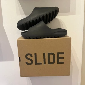 Yeezy slides  - Säljer ett par äkta yeezy slides onyx i storlek 42. Dom är andvända och har lite slitage längst fram annars är dom i bra skick 9/10. Låda, kvitto och tags följer såklart med. Har man några frågor eller vill ha mer bilder är det bara att höra av sig 😁